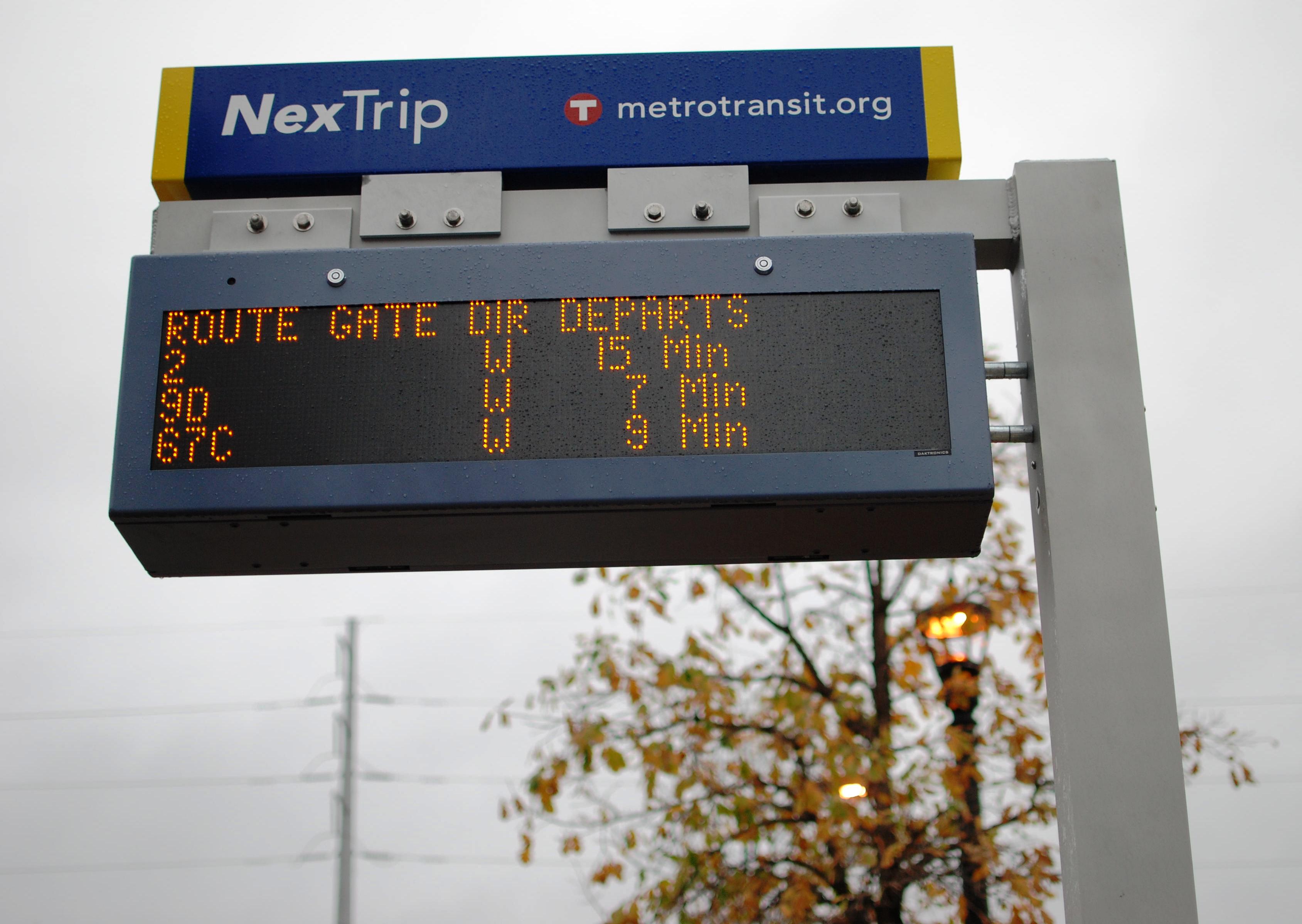 A NexTrip sign provides expected real-time departures for upcoming bus trips. The sign posts also have a button for audio information.