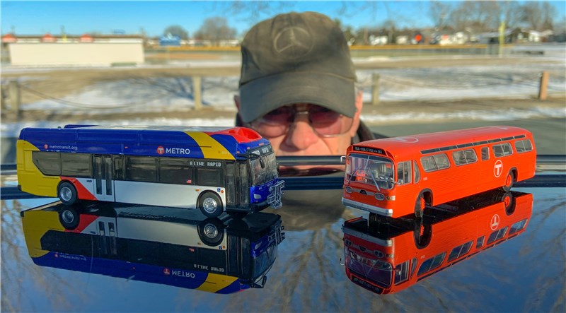 A man with two model buses.