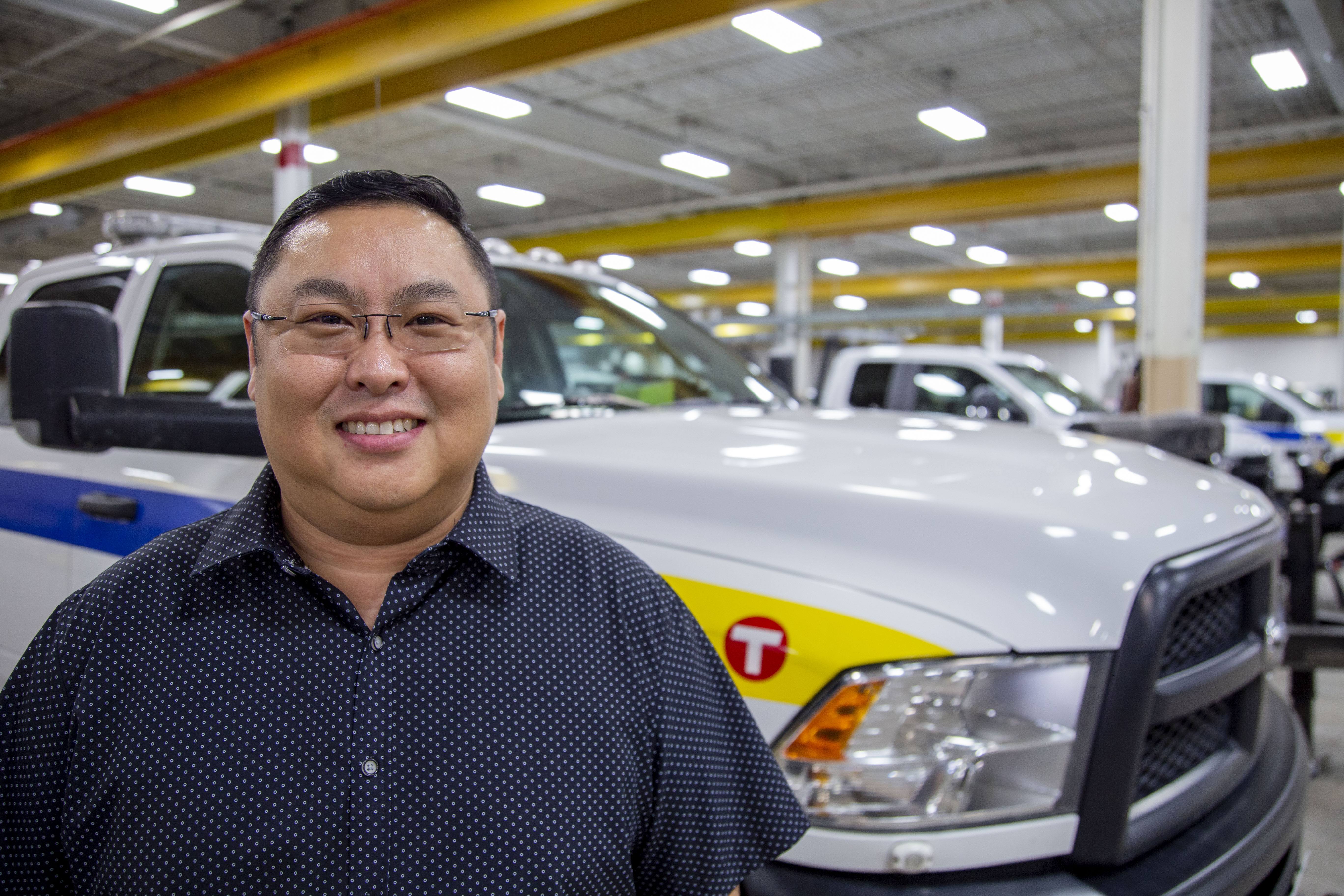 Public Facilities Maintenance Supervisor Kou Xiong stands in front of a truck. 