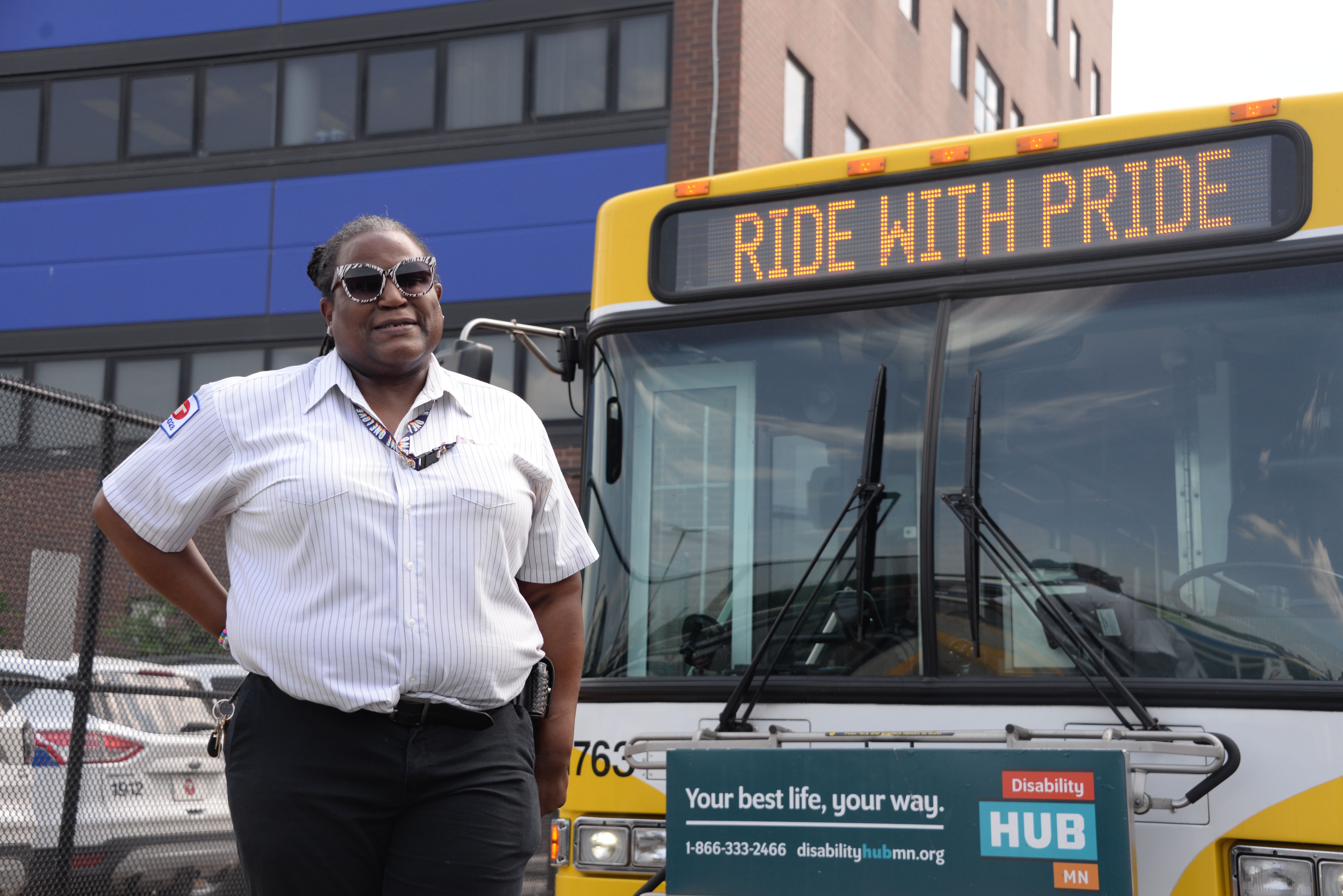 Metro Transit bus operator Marissa Higgins next to a bus that says "Ride With Pride."