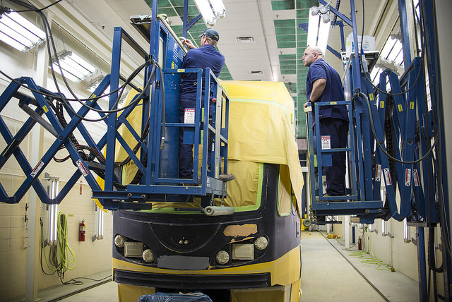 Brooks Letourneau and Robert Whebbe apply tape before another round of painting on a light-rail vehicle.