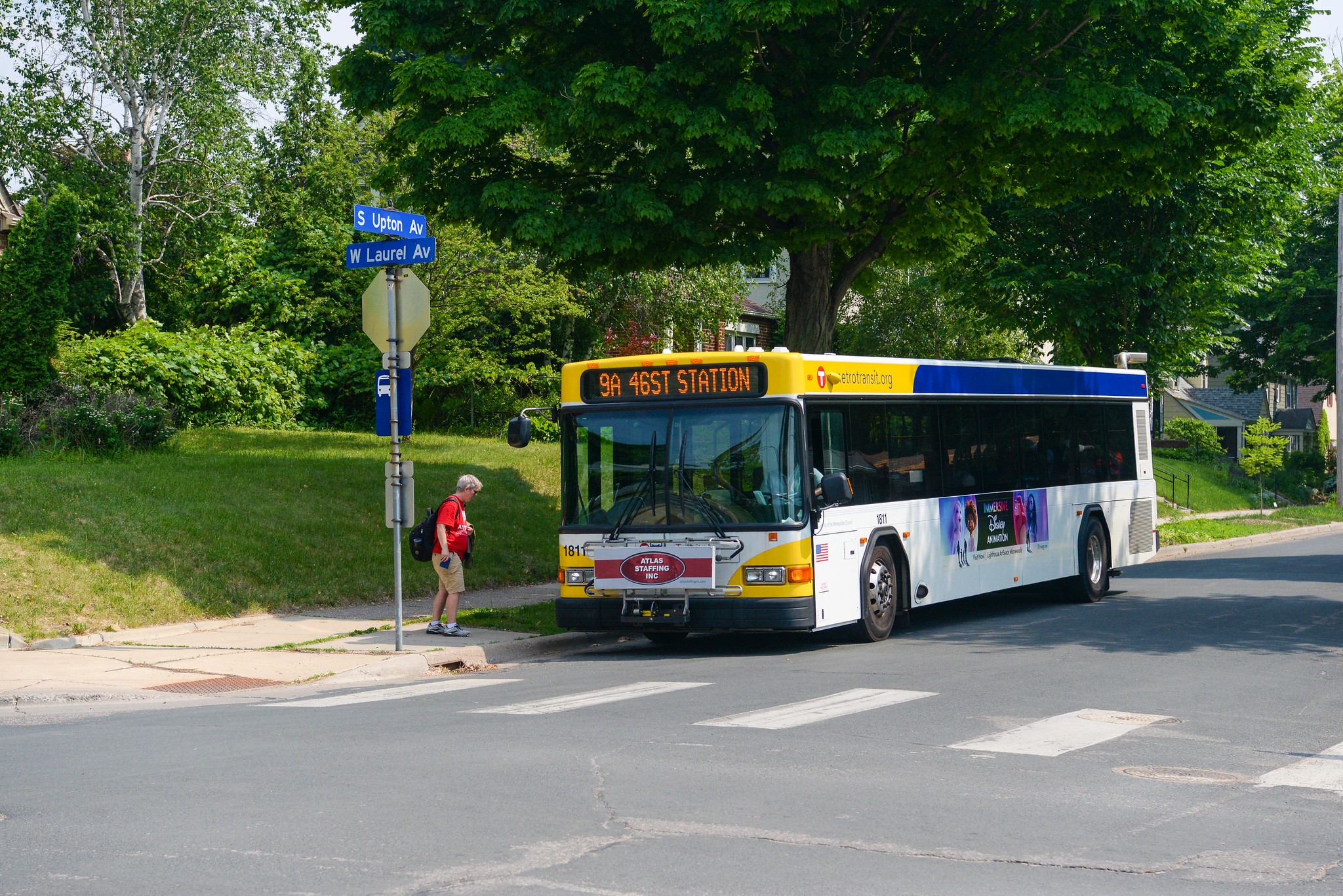 A Route 9 bus approaches a bus stop as a customer prepares to board. 
