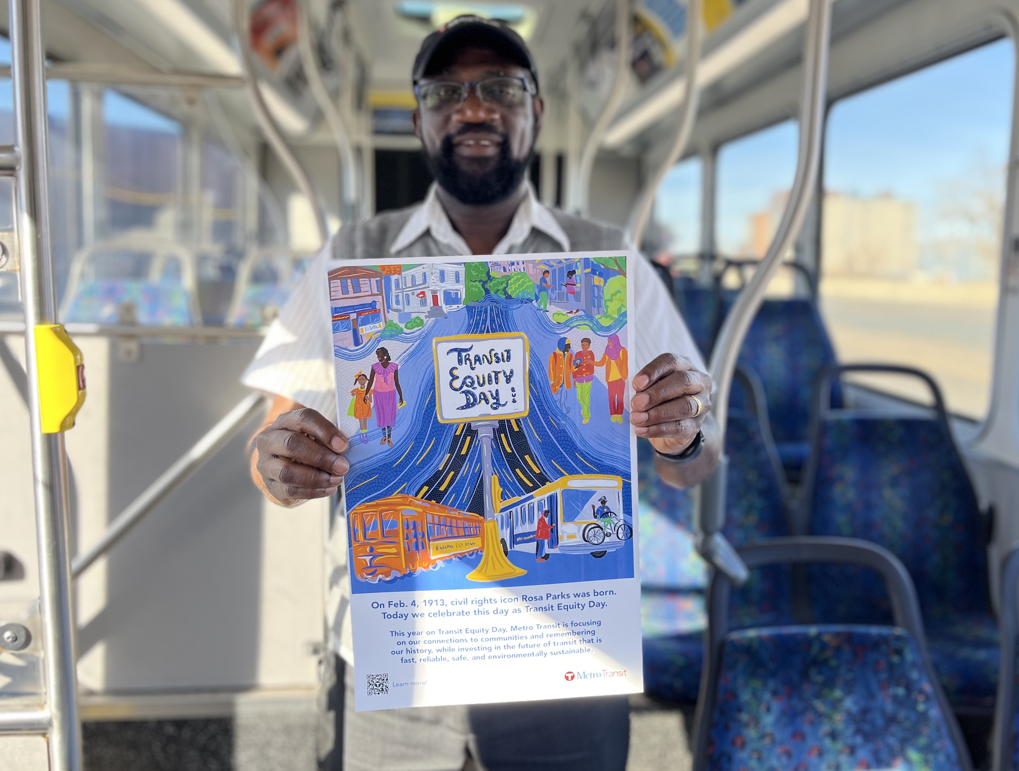 A bus operator holds a Transit Equity Day poster.