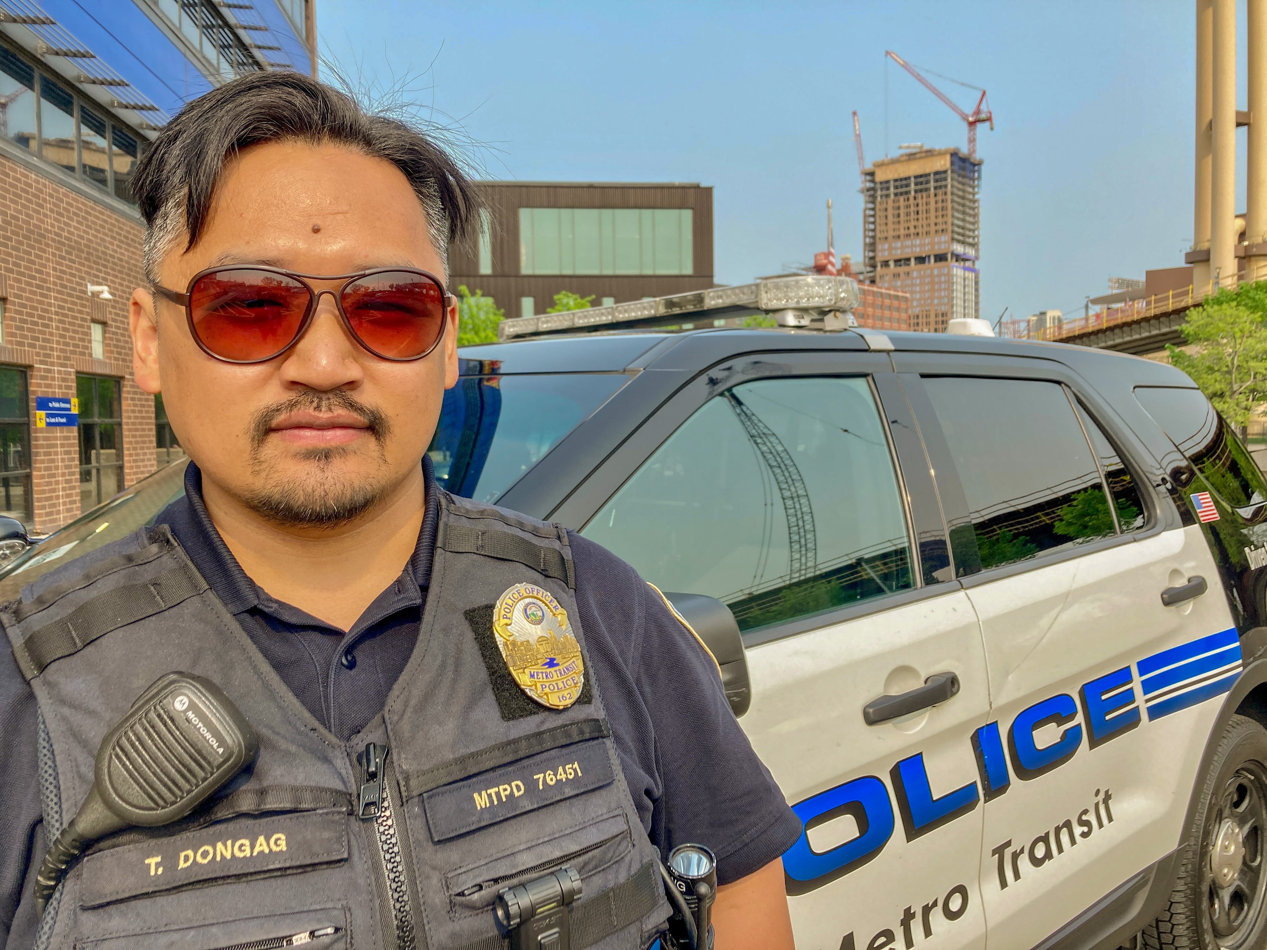 Police Officer Tenzin Dongag stands in front of a squad car outside the Metro Transit Police Department.