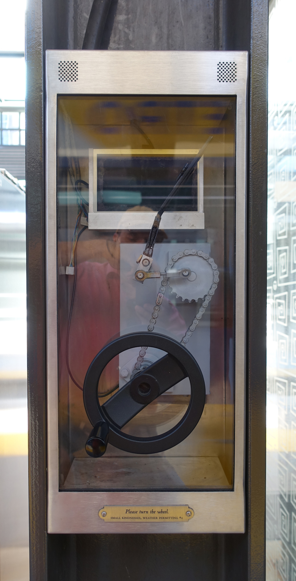 Title: Please turn the wheel Material: Stainless Steel box, glass, audio and video components, speaker, wheel mechanism, wiper, chain, cogs and title plate.