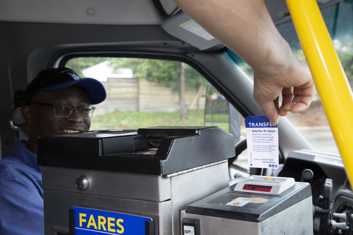 A micro driver looks on as a customer inserts a transfer into the farebox