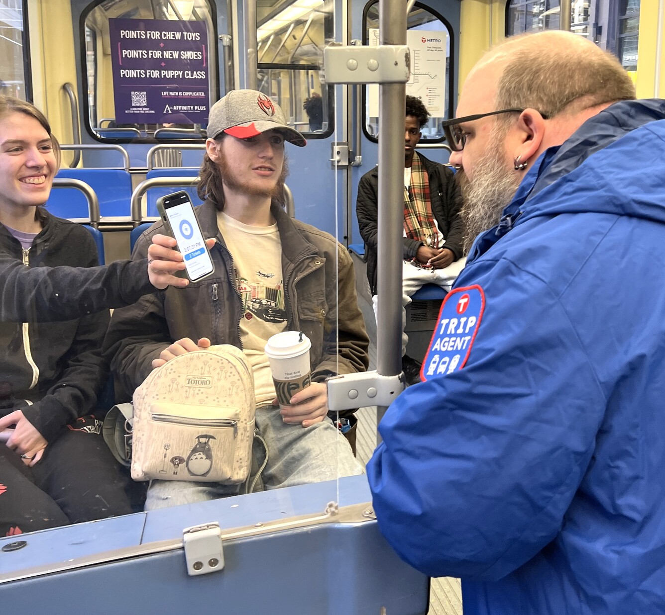 Customers show proof of fare payment to a TRIP Agent on a METRO train