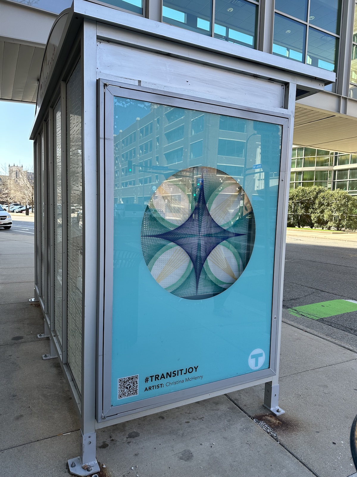 Two people installing artwork at a bus shelter.