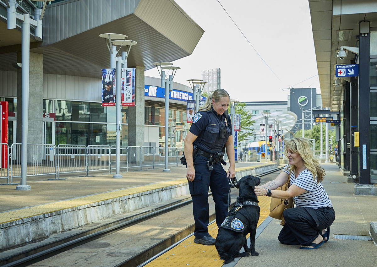 Transit Police Officer and K-9 officer at a rail station with a customers